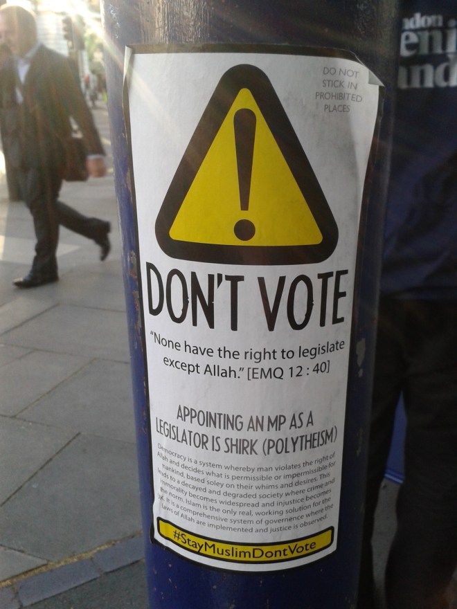 A sticker calling for Muslims not to vote. Some argue that voting is polytheism, because no one has the right to make laws except God. The sticker has an official appearance, looking more like a warning sign than a protest sticker (Euston Station, 12/05/15). 